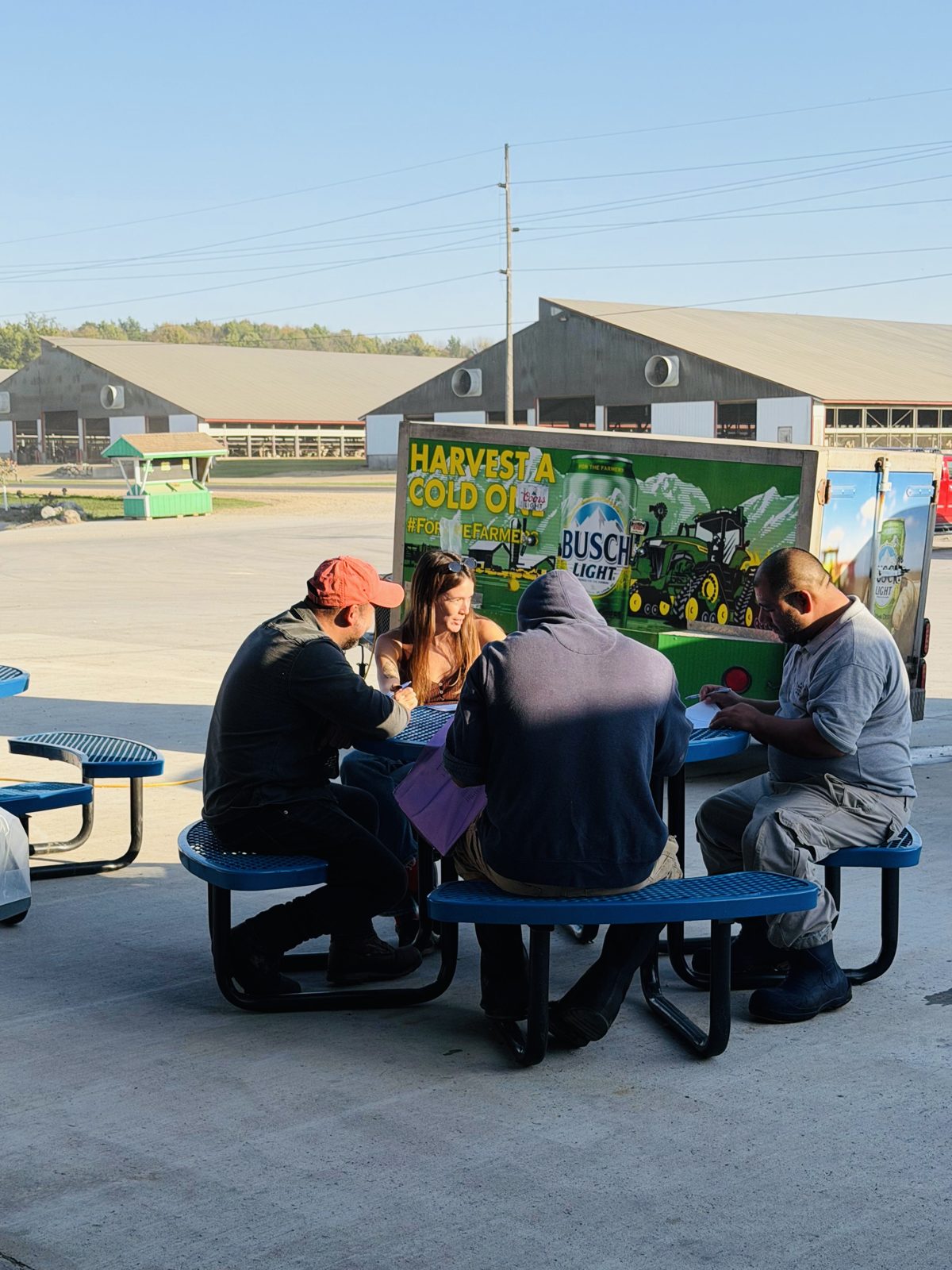 Lola conducting surveys with dairy workers at a picnic table on a Wisconsin farm